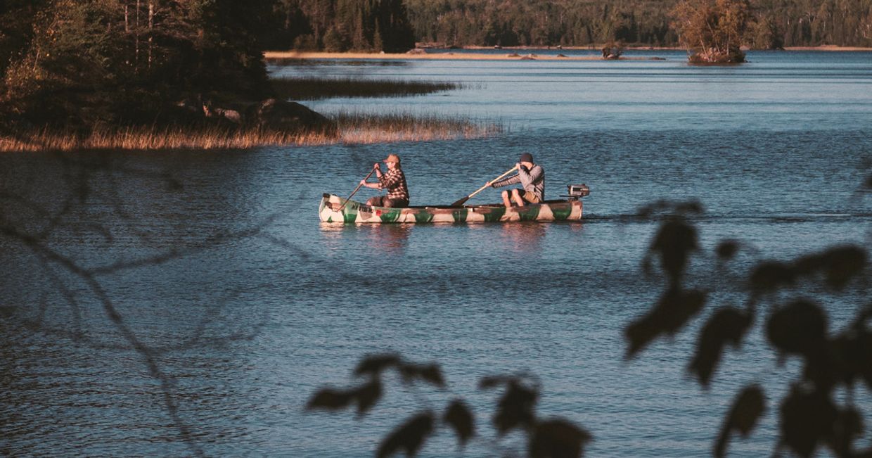Dwie osoby wiosłujące w kajaku na jeziorze. (fot. Aaron Huber / unsplash.com)