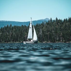 Żaglówka z białym żaglem na jeziorze (fot. Chris Maestas / unsplash.com)