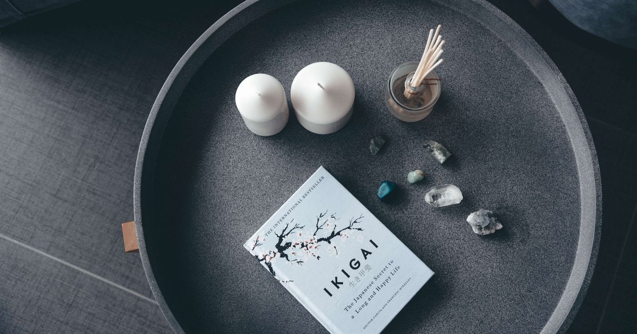 Poradnik o IKIGAI leżąca obok kamieni szlachetnych i świeczek zapachowych (fot. Content Pixie)