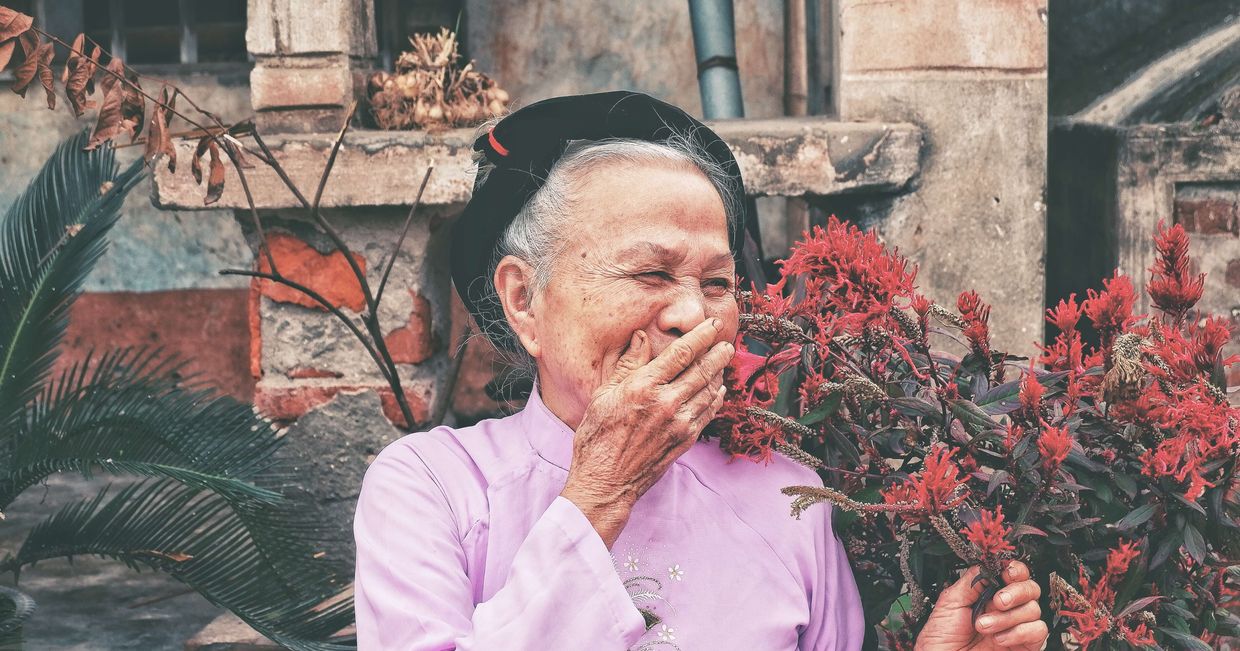 Śmiejąca się starsza kobieta w ogrodzie (fot. Huyen Nguyen / unsplash.com)