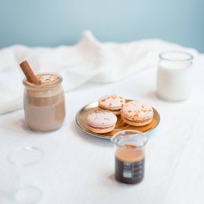 Cappuccino z cynamonem, makaroniki, mleko i espresso na białym obrusie (fot. Martyna Cybuch)