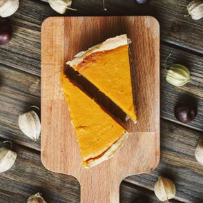 Dwa kawałki tarty dyniowej na drewnianej desce