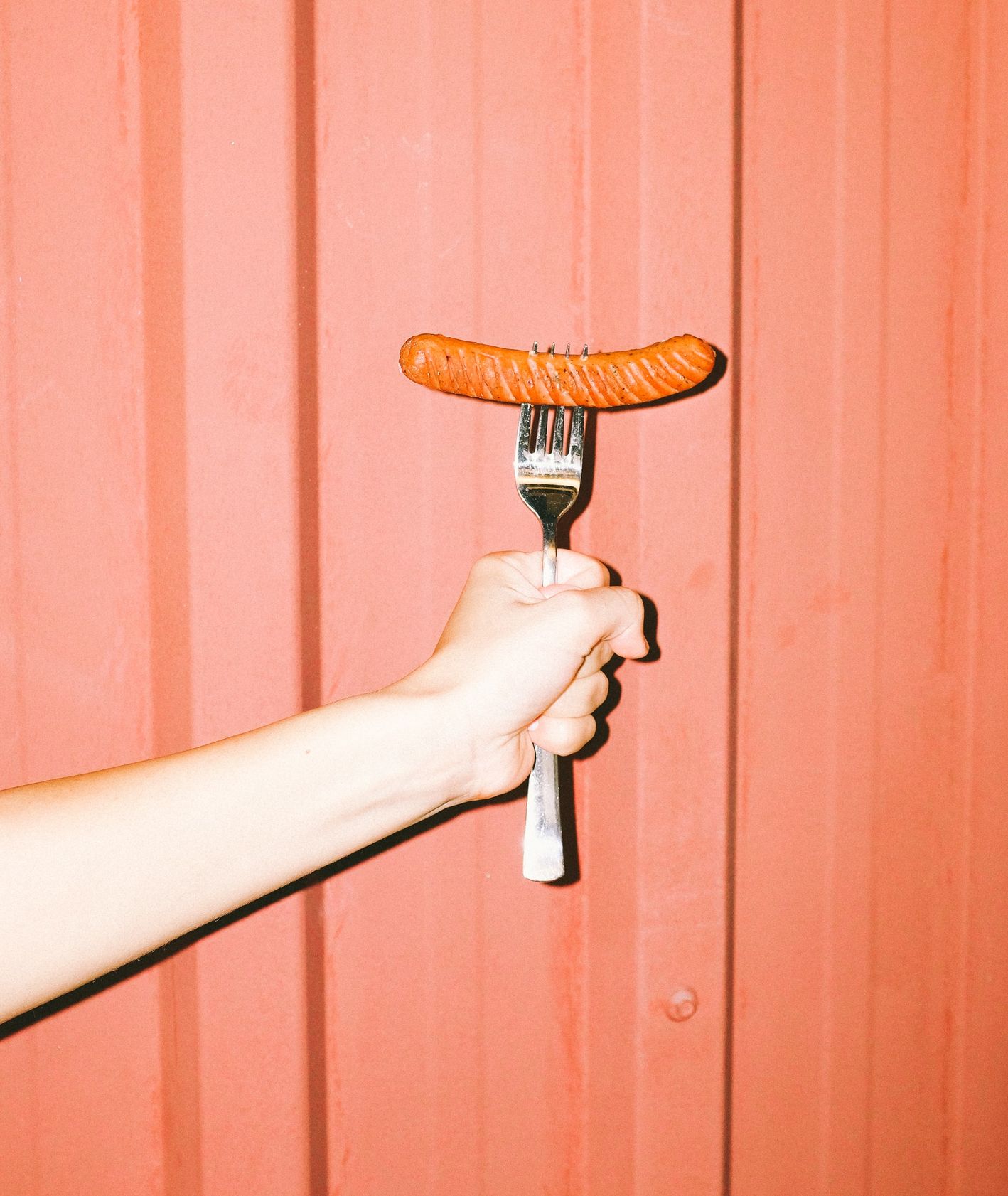 Ręka trzymająca widelec z wegańską parówką (fot. Yasin Aribuga / unsplash.com)