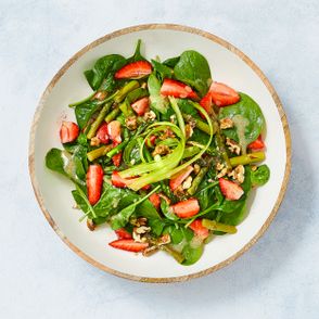 Lekka sałatka wiosennna z zieolnych szparagów ze szpinakiem baby i świeżymi truskawkami posypana orzechami włoskimi, podana z sosem vinegrette miodowo-musztardowym