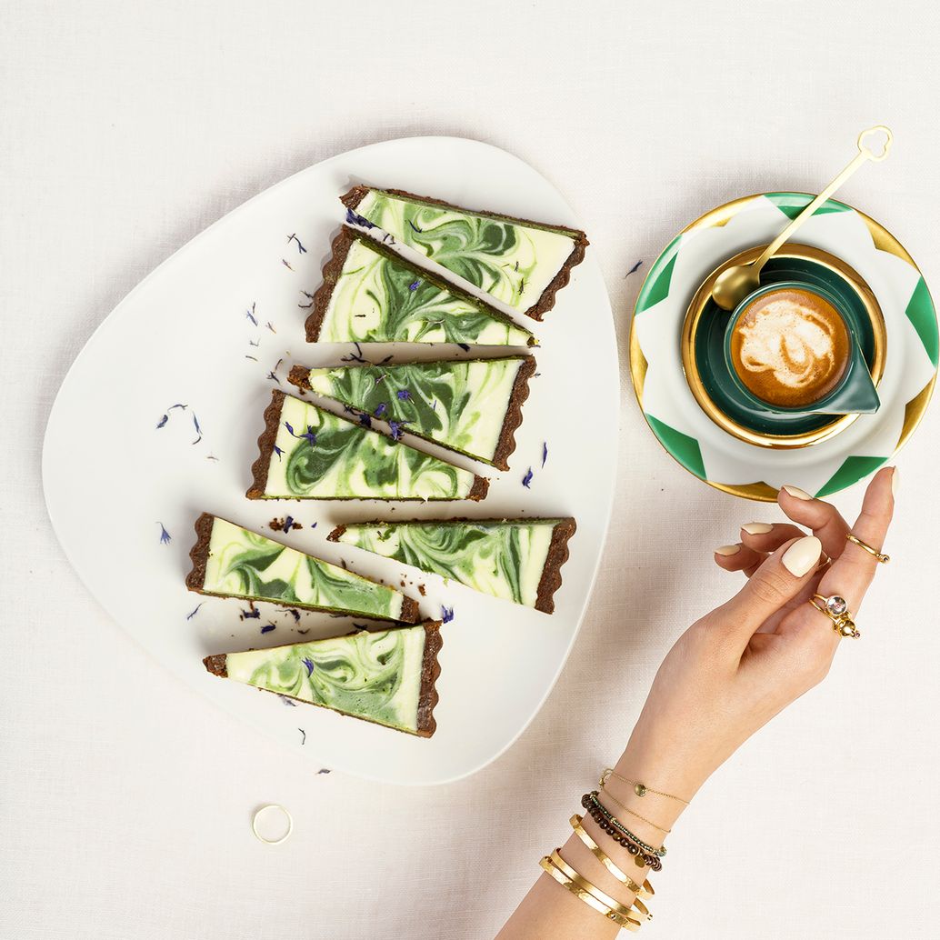 pokrojony mazurek z matchą, oraz filiżanka z kawą.