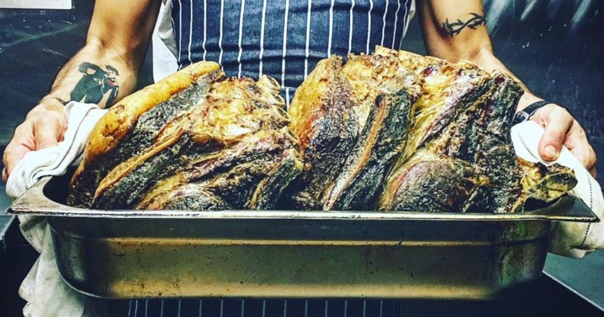 Eryk Bautista w kuchni niosący grillowane mięso