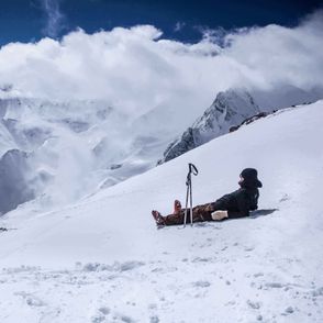 Mężczyzna w kombinezonie narciarskim leżący na stoku