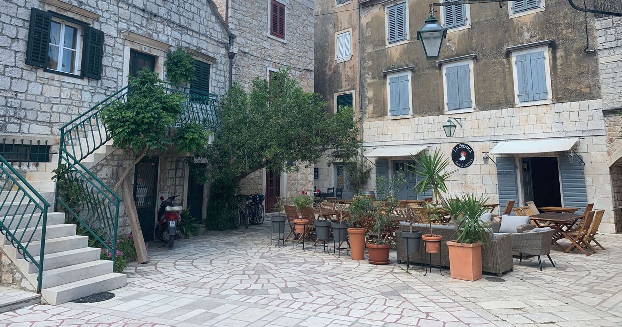 Widok na kamienice i ogródek restauracji w mieście Stari Grad na wyspie Hvar w Chorwacji