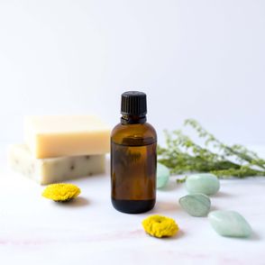 Olejek w brązowym flakoniku, kostki mydła, kamyki i kwiaty (fot. Sarah Gualtieri / unsplash.com)