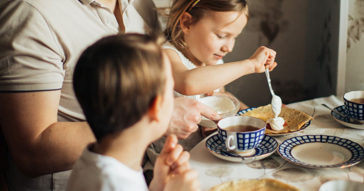 Rodzina jedząca śniadanie przy stole. (fot. Elly Fairytale / pexels.com)