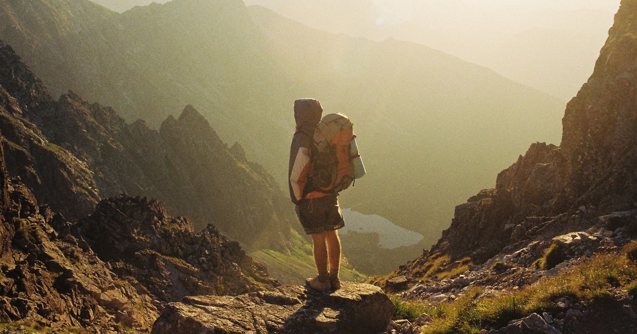 Mężczyzna z plecakiem stojący w górach (fot. Danka Peter / unsplash.com)