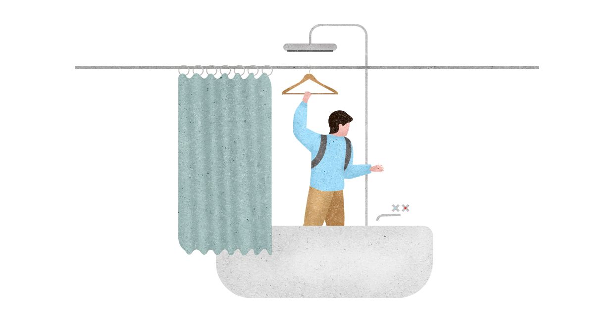 Mężczyzna w wannie, trzymający wieszak zawieszony na ramie zasłonki prysznicowej (il. Marcin Lewandowski)