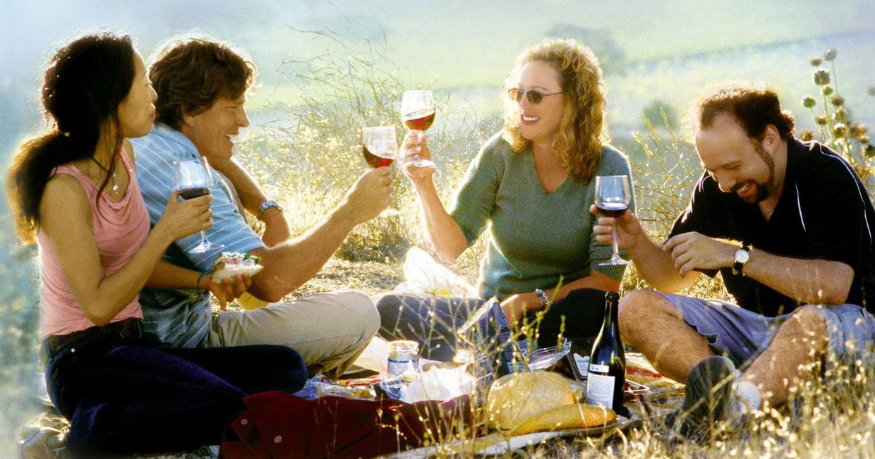 Jack, Miles i ich dwie tajemnicze towarzyszki piją wino podczas pikniku – kadr z filmu "Bezdroża"