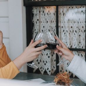 Para stukająca się kieliszkami z czerwonym winem w restauracji (fot. Nate Johnston / unsplash.com)