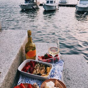 Włoskie wybrzeże, piknik nad rzeką – wino, pieczone warzywa, pieczywo, w tle zacumowane łódki (fot. Daria Litvinova)