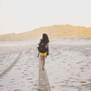 Kobieta z plecakiem idąca plażą (fot. Amy Fraser / unsplash.com)