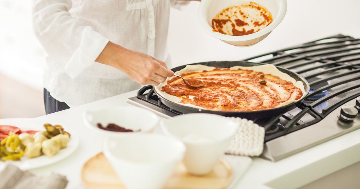 Przygotowanie pizzy - nakładanie sosu (fot. Dinnershow Studio)