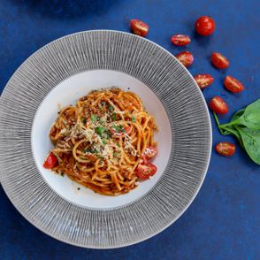 Proste spaghetti pomidorowe z bazylią i parmezanem na niebieskim obrusie (fot. Danijela Prijovic / unsplash.com)