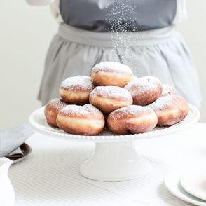 Osoba posypuje pączki cukrem pudrem (fot. Dinershow.studio)