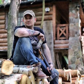 Mężczyzna siedzący na stosie ściętych drzew