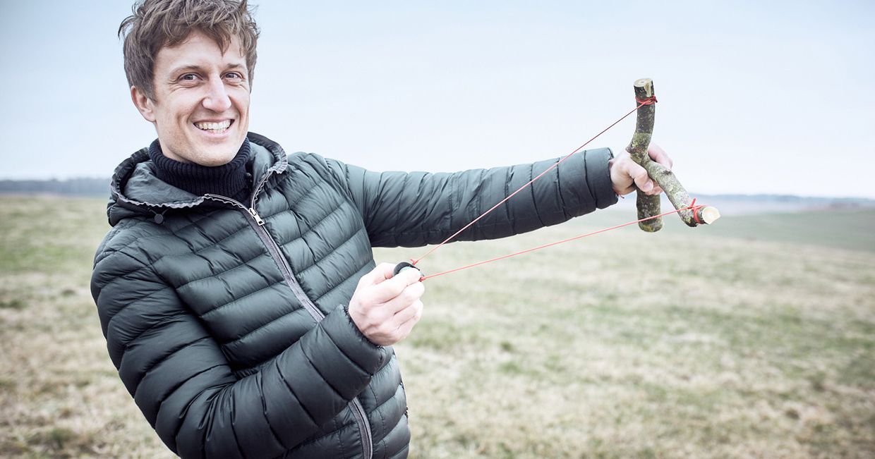 David Gaboriaud z procą w dłoni, podczas wysiewania dzikich kwiatów na łące za pomocą seed balls, kulek wypełnionych nasionami