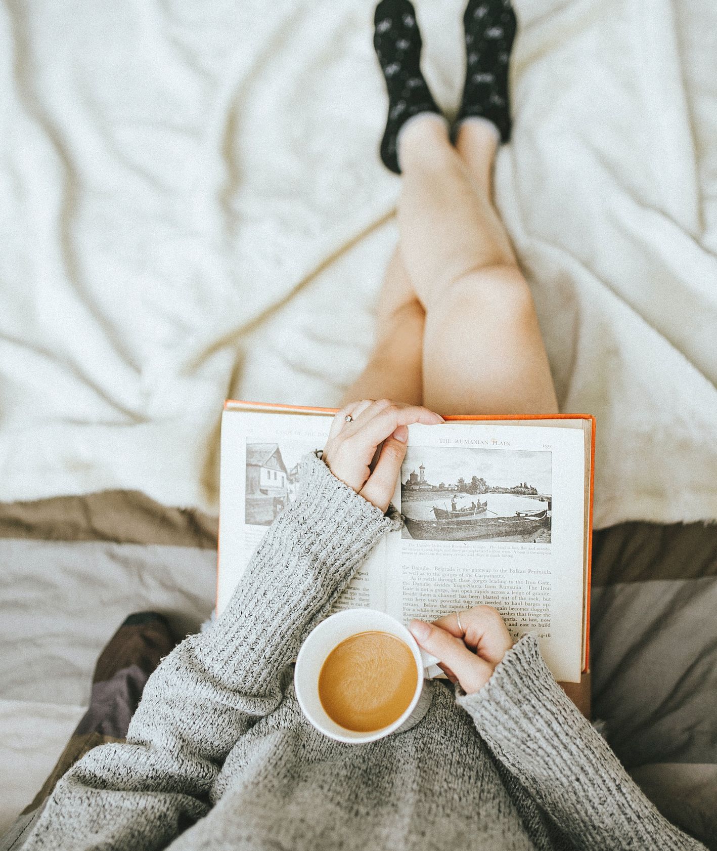 Dziewczyna czytająca książkę z kubkiem kawy w dłoni, jesienny relaks, (fot. Anthony Tran / unsplash.com)
